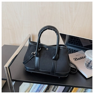 Detail of black suede and leather bucket bag with silver hardware on office desk