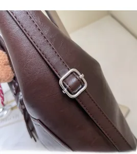 Detail of dark brown leather tote strap with adjustable silver metal buckle and stitching