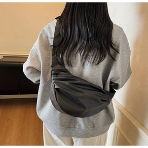 Detail of minimalist black crossbody bag with horizontal pleats and adjustable strap