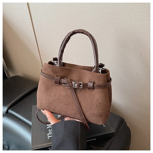 Detail of brown faux suede bucket bag with decorative buckle and PU handle close-up