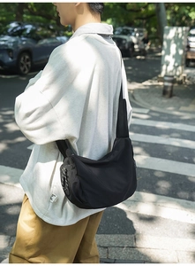 Vista laterale della borsa messenger nera in nylon con cerniera per uno stile casual