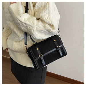 Close-up of vintage black crossbody bag featuring gold buckles and adjustable strap on a model