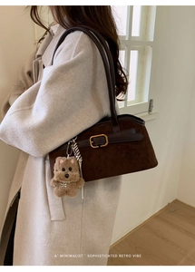 Dettaglio borsa vintage scamosciata caffè scuro con ciondolo a forma di cane e fibbia d'oro
