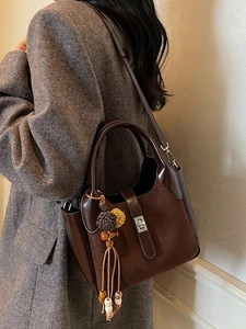 Vintage brown frosted bucket bag with tassel detail worn on a grey tweed coat