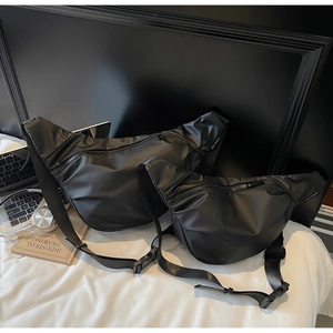 Detailed macro shot of two minimalist black nylon crossbody bags in small and large sizes