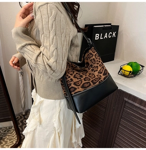 Detail of leopard print suede tote bag featuring sleek leather trim and metal zipper