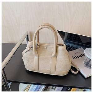 Detail of apricot suede and leather bucket bag with top handles on a desk