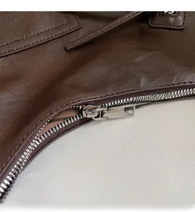 Macro detail of the smooth silver metal zipper on the brown textured leather tote bag