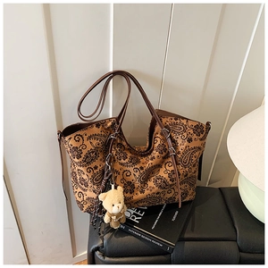 Close-up of vintage paisley print tote bag with brown straps and a cute plush bear charm