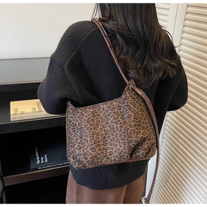 Chic leopard print hobo bag with brown leather strap shown on a female shoulder