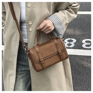 Detail of brown vintage suede crossbody bag with decorative buckles and crossbody strap