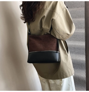 Detail of suede and leather bucket bag with silver zipper on a trench coat model