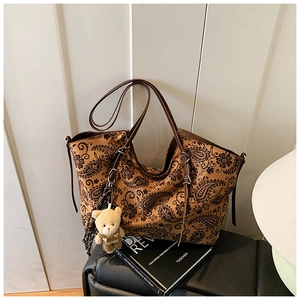 Detail of vintage paisley print tote bag with cute brown teddy bear plush pendant