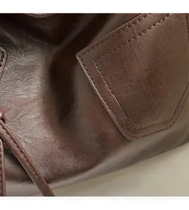 Detailed macro view of dark brown leather tote bag with fine stitching and drawstrings