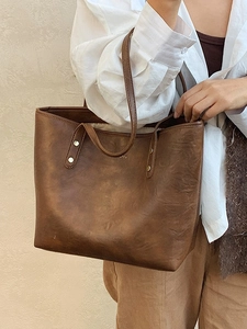 Brown vintage faux leather tote bag with gold rivets shown on a model for daily use