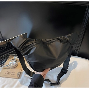 Close-up of black crossbody dumpling bag with adjustable strap on a minimalist desk setup