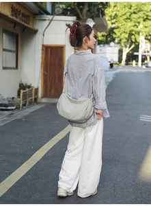 Borsa a tracolla minimalista in tela grigio chiaro indossata da una modella urban