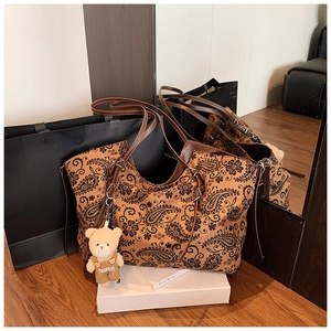Detail of vintage paisley tote bag in tan with black floral patterns and teddy charm