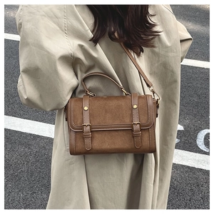 Close-up of retro brown tote bag featuring mixed textures and classic double buckle straps