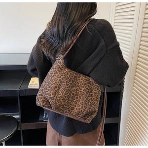 Detailed back view of a soft leopard print shoulder bag with dark brown strap on a model