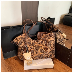 Detail of vintage paisley tote bag with brown leather straps and a cute teddy bear charm