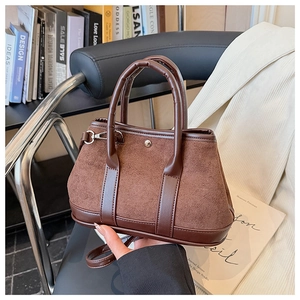 Detailed view of vintage brown suede tote with leather handles and metallic rivet accents