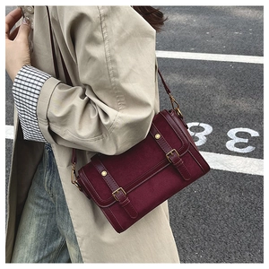 Outdoor street style view of a burgundy patchwork leather crossbody bag on a trench coat