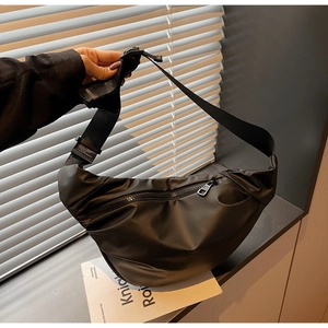 Close-up of black nylon dumpling bag featuring adjustable strap and quick-release buckle