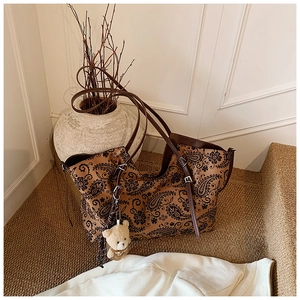Detail view of coffee brown paisley tote bag with slender straps and cute bear charm