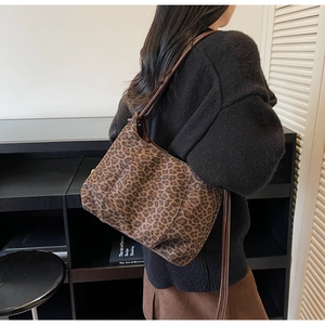 Detail of leopard print shoulder bag with brown leather strap worn by a model