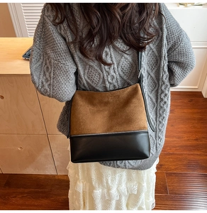 Detail of minimalist dual-texture crossbody bag featuring brown suede and black leather
