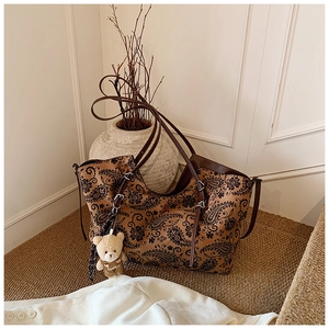 Detail of vintage paisley tote bag with dark brown leather handles and bear charm