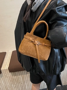 Brown frosted leather crossbody bucket bag shown on model in a minimalist wooden setting