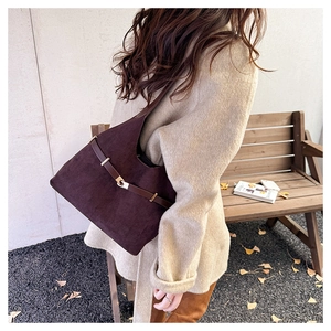Detail of vintage burgundy suede tote bag styled with an oatmeal wool coat outdoors