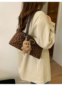 Dettaglio borsa leopardata con ciondolo a cane di peluche su un trench beige