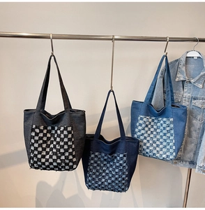 Trois sacs cabas en jean avec poches à damiers suspendus sur un support en métal poli