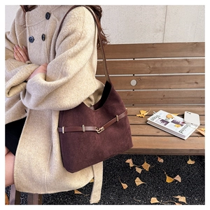 Close-up of dark brown suede tote bag with metallic buckle detail in autumn street style