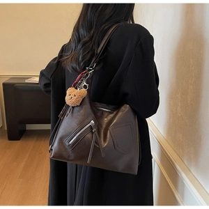 Detail of vintage brown tote bag with zipper pocket and cute plush bear charm accessory