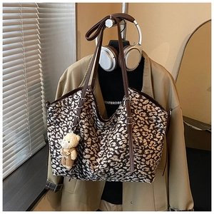 Detailed shot of large leopard print tote bag with brown leather straps and bear charm