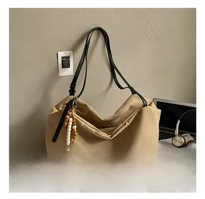 Detail of khaki canvas tote bag with black leather strap and colorful beaded charm