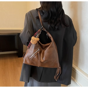 Close-up of a large brown vintage faux leather shoulder bag with plush bear charm detail