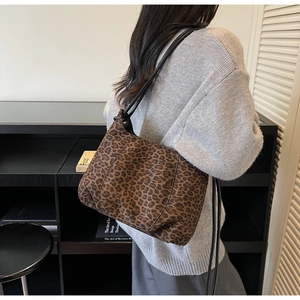 Shoulder view of a leopard print tote bag with black straps on a fashion model