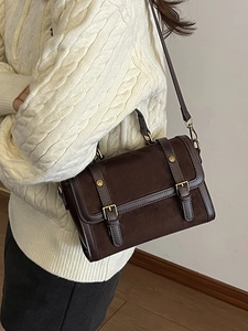 Vintage dark brown crossbody bag with dual buckles shown on a model in a minimal room
