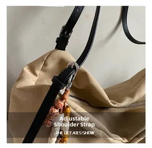 Detail of canvas tote bag with adjustable leather shoulder strap and beaded tassel charm