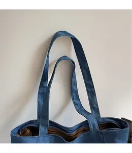 Détail du cabas en jean bleu montrant la fermeture éclair et la doublure rayée