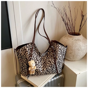 Detail of vintage leopard print tote bag with brown leather straps and plush bear charm