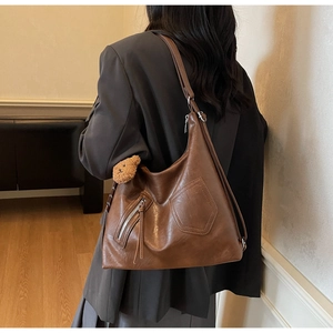 Detail of retro brown faux leather tote bag with side bear charm and zip pocket