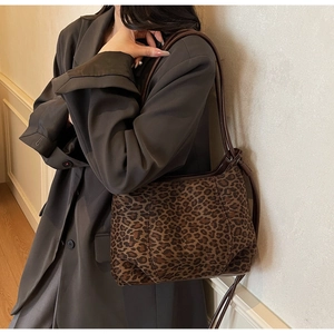 Detailed view of leopard print texture on a stylish baguette bag with brown leather strap