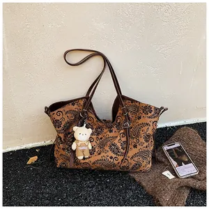 Detailed view of brown tote bag with paisley pattern and cute bear doll pendant
