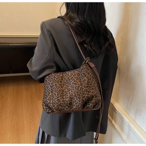 Detailed view of leopard print canvas bucket bag with brown leather shoulder strap on model